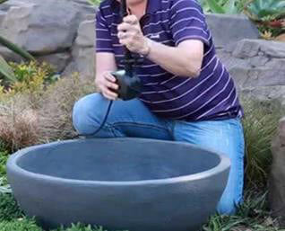 A man gently cleaning a ceramic water fountain
