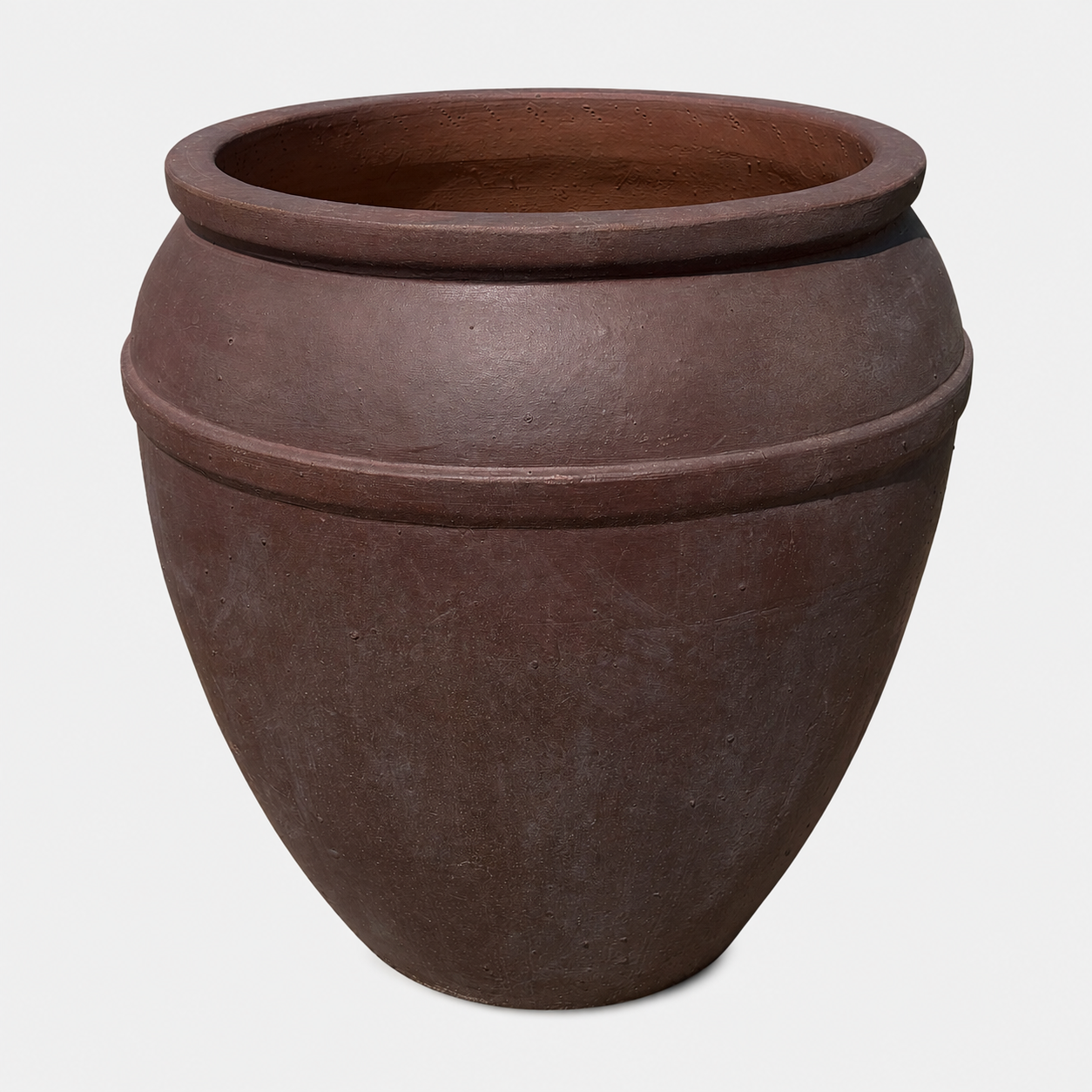 A large, brown textured ceramic planter with a wide rim and subtle horizontal ridges, shown against a plain light gray background.