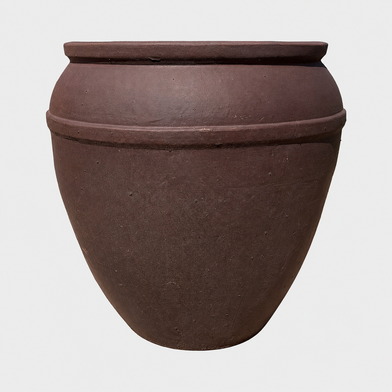 A large, brown clay planter with a wide rim and two horizontal decorative ridges, shown against a plain light gray background.