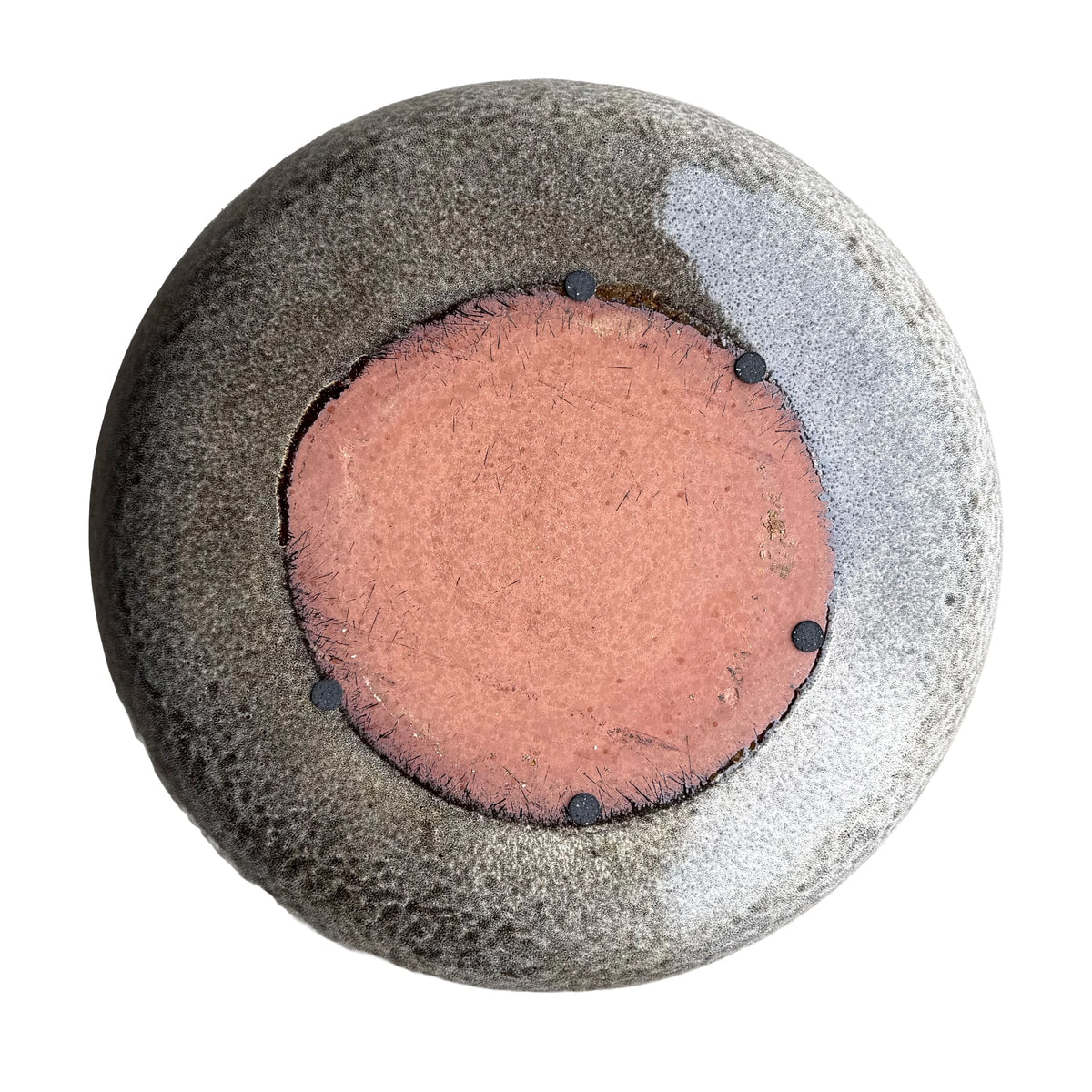 Underside of a Speckle Black ceramic bird bath bowl, with an unglazed terracotta base, five small dark pads, and a speckled black glaze.