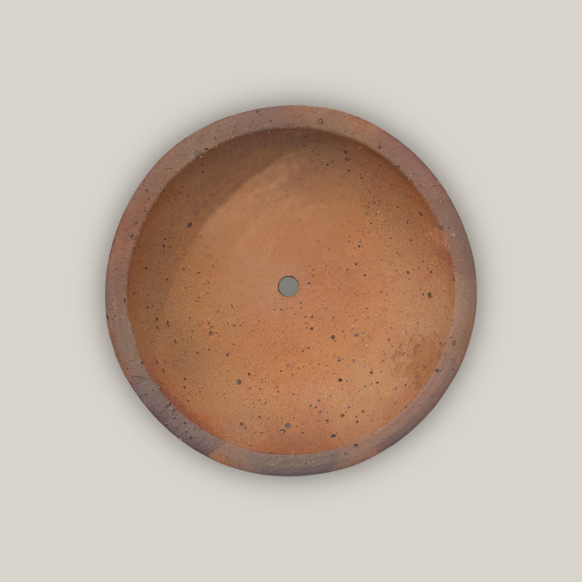 Looking straight down into the Iron Clay Rustic Style Wide Bowl, its smooth terracotta basin and central drainage hole are framed by a thick, earthy clay rim.