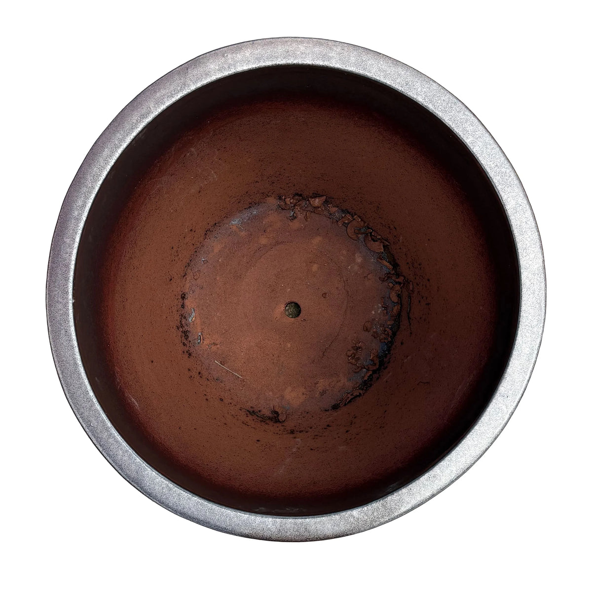 Top view of an oxide tapered round ceramic planter, with a pewter-toned rim and dark inner walls that open onto a terracotta floor with a raised centre and small drainage hole