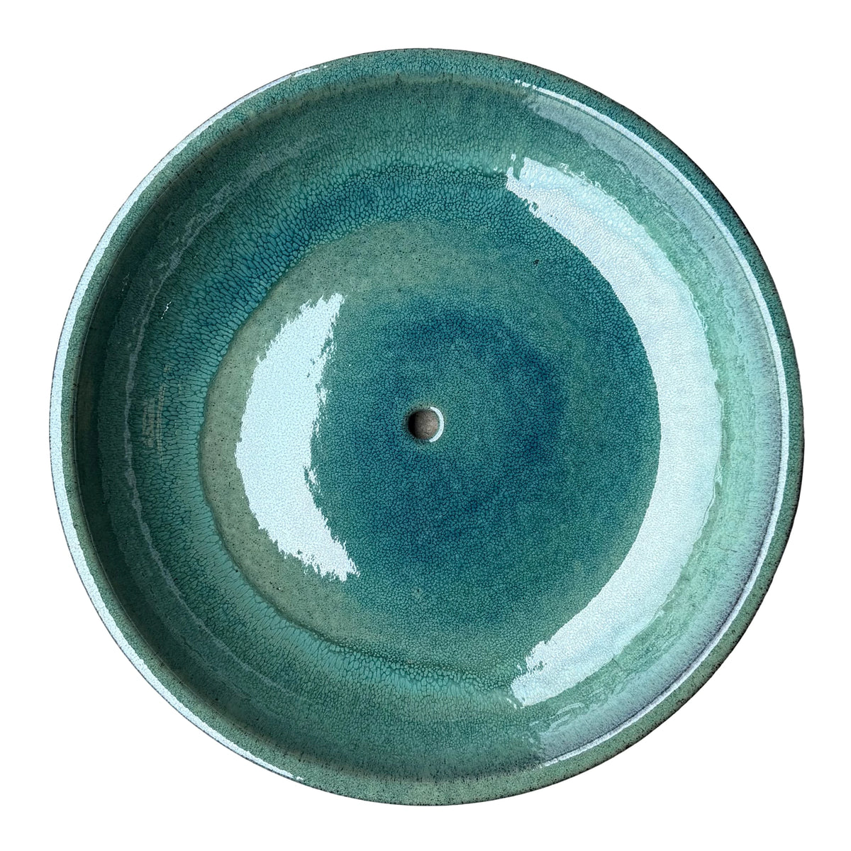 Top-down view inside a teal ceramic succulent bowl, where a glossy, finely pebbled glaze shifts from sea green at the rim to deep blue around the drainage hole