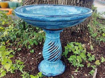 Red ceramic birdbath displayed in a garden
