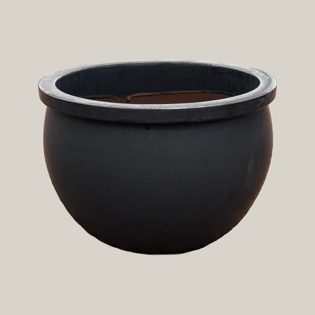 Matte black round bowl planter with wide low-profile silhouette, slightly angled view highlighting its smooth matte finish