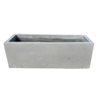 Low grey rectangular fiberstone planter shown from the front with a slight top angle, highlighting its low-profile rectangular form and clean stone-look finish.