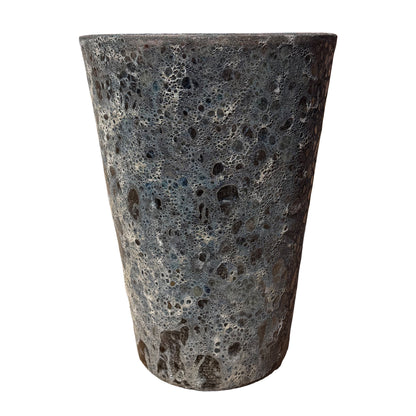 Front view of a textured, tapered planter pot with a highly porous, bubbled surface and a dark charcoal gray finish, shown against a plain white background.