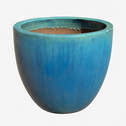 A ceramic planter with a rounded, wide rim shape, featuring a textured blue glaze with a subtle greenish-teal undertone and a brown clay interior, shown against a plain white background.
