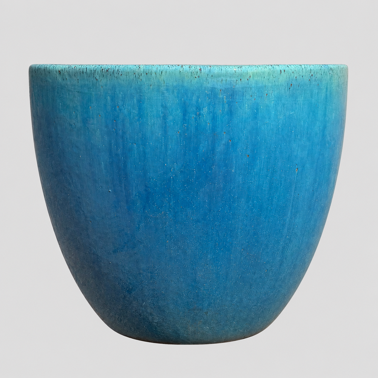 A wide, rounded ceramic planter with a textured blue glaze, shown against a solid light gray background.
