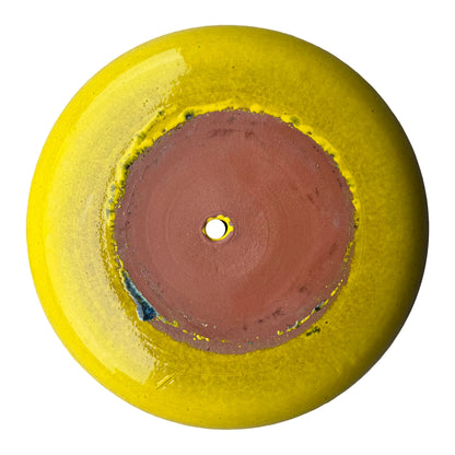 Underside of an atomic yellow ceramic succulent bowl, showing an unglazed terracotta base with a central drainage hole, framed by a ring of glossy lemon-yellow glaze