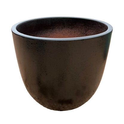 Angled view of a black tapered round ceramic planter, showing its pitted dark exterior, a smooth rounded rim and a speckled interior that shades into terracotta
