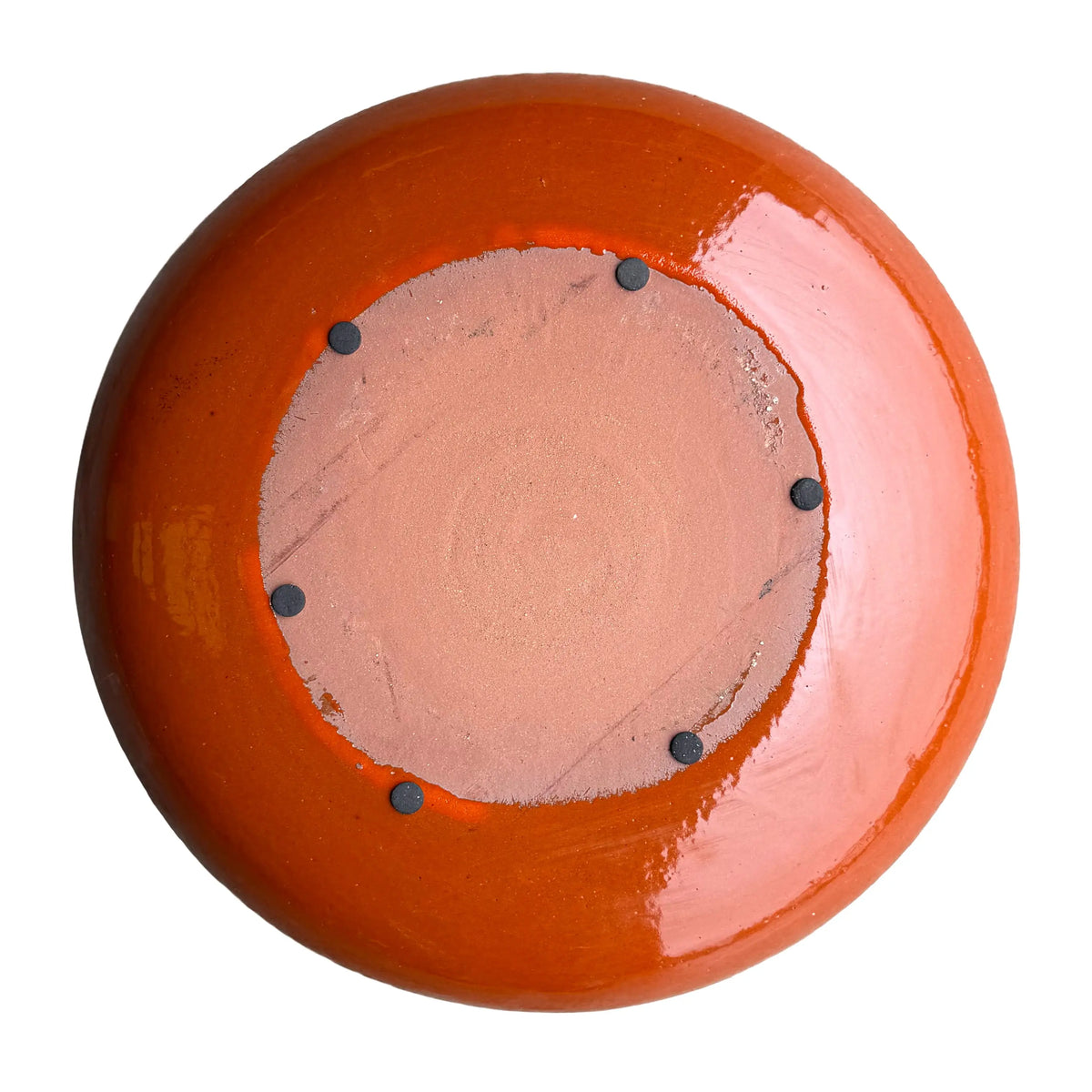 Underside of an Atomic Orange ceramic bird bath bowl, with an unglazed terracotta base ringed by six small dark pads.