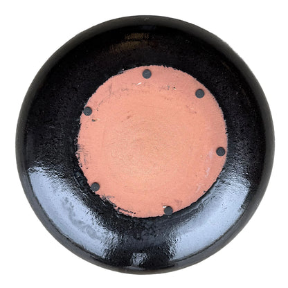 Underside of a Black Tiger ceramic bird bath bowl, with an unglazed terracotta base, six small dark pads, and glossy black glaze.