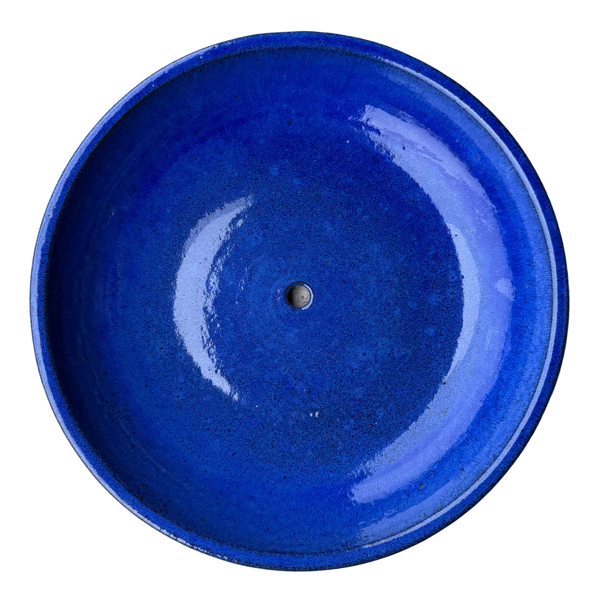 Top-down view of a Falling Blue ceramic succulent bowl, showing a glossy royal blue basin with fine dark speckles and a center drainage hole.