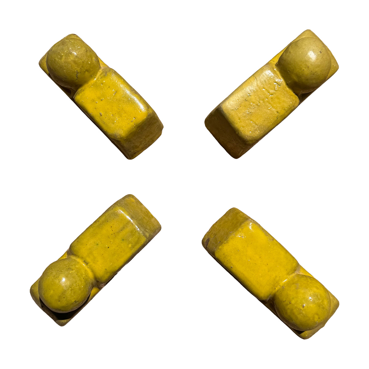 Four yellow ceramic Bari pot feet arranged in an X pattern to show spacing under a planter.