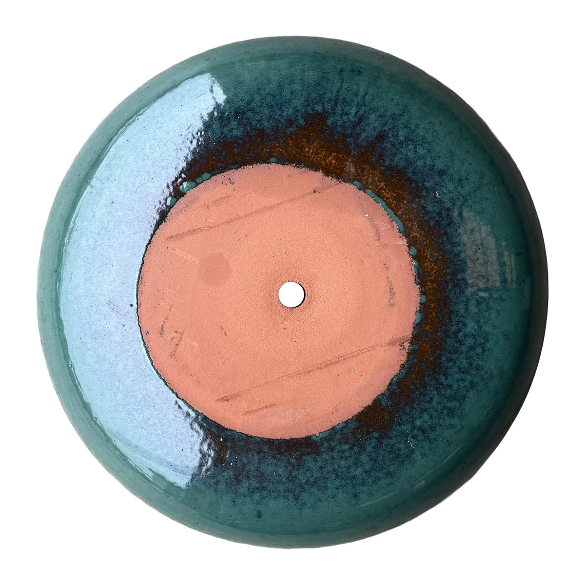 Underside of a jade ceramic succulent bowl, with an unglazed terracotta base, a drainage hole, and a rust-brown ring blending into green.
