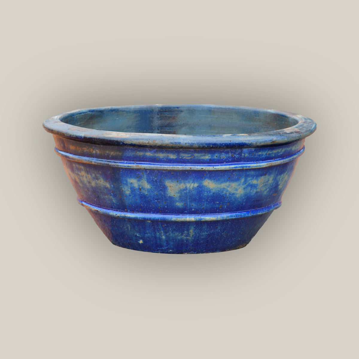 Midnight Blue rustic low bowl ceramic planter, slightly angled from above, with a rolled rim, raised rings, and amber-washed glaze.