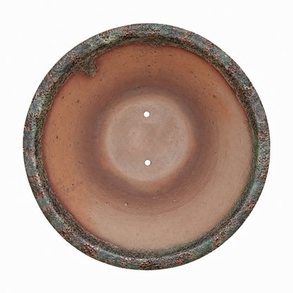 Looking straight down into the Midnight Green Giant Cone Ceramic Planter, its sun-warmed terracotta interior and drainage holes framed by a rugged rim streaked with green patina and rusty copper tones.