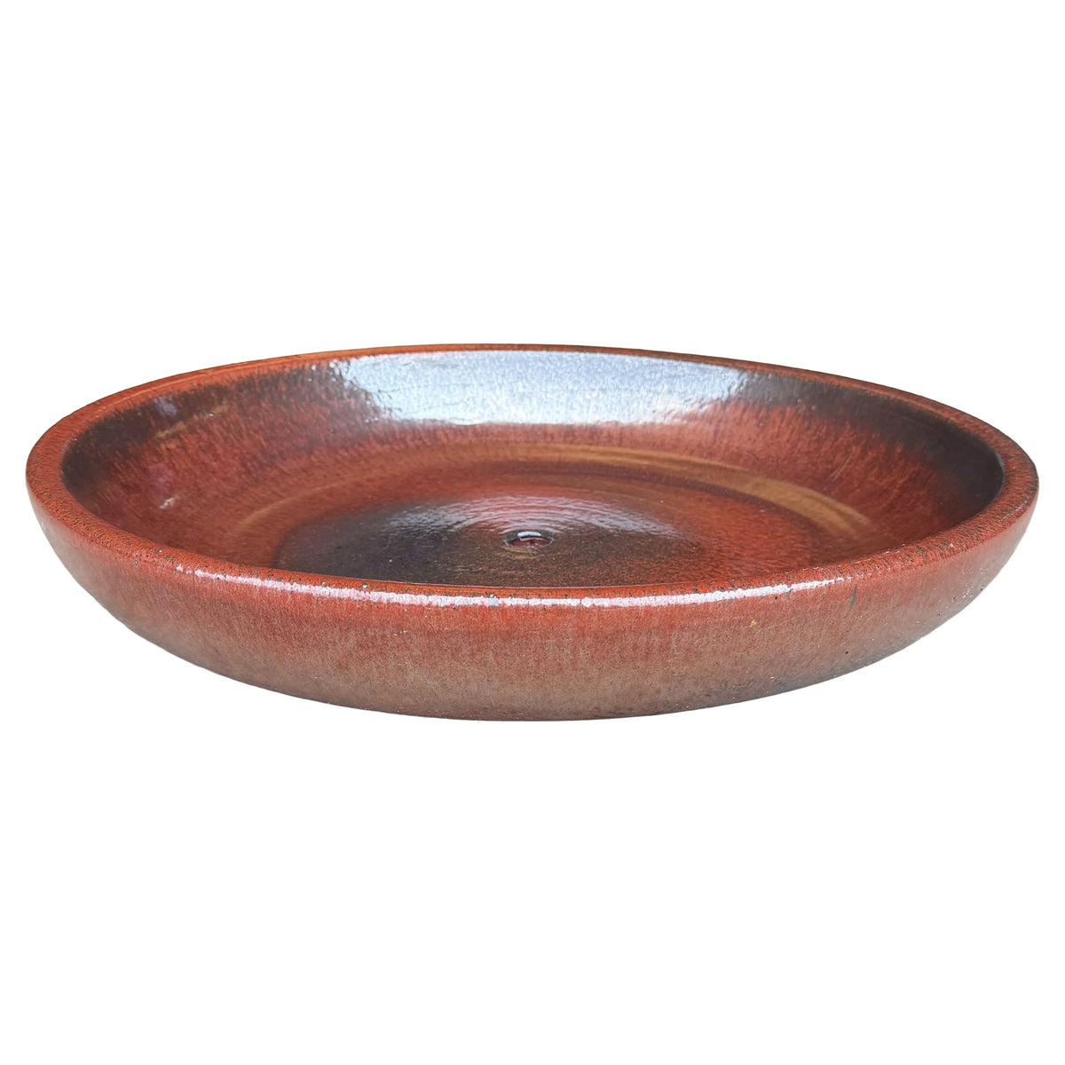 Angled view of a wide, shallow oxide ceramic succulent bowl in glossy rust-red glaze, with a speckled rim and a darker center around the drainage hole