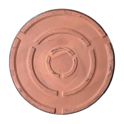 Underside of a round teal ceramic plant saucer, showing an unglazed terracotta base with raised concentric ring feet and a thin edge of teal glaze around the rim