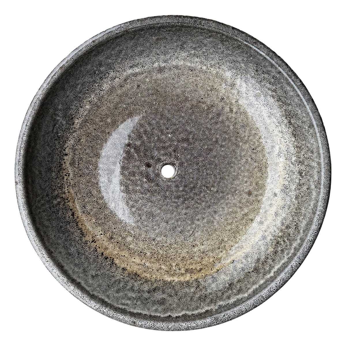 Top-down view inside a speckle black ceramic succulent bowl, where a mottled grey glaze shifts to a golden-tan ring and a darker speckled center around the drainage hole