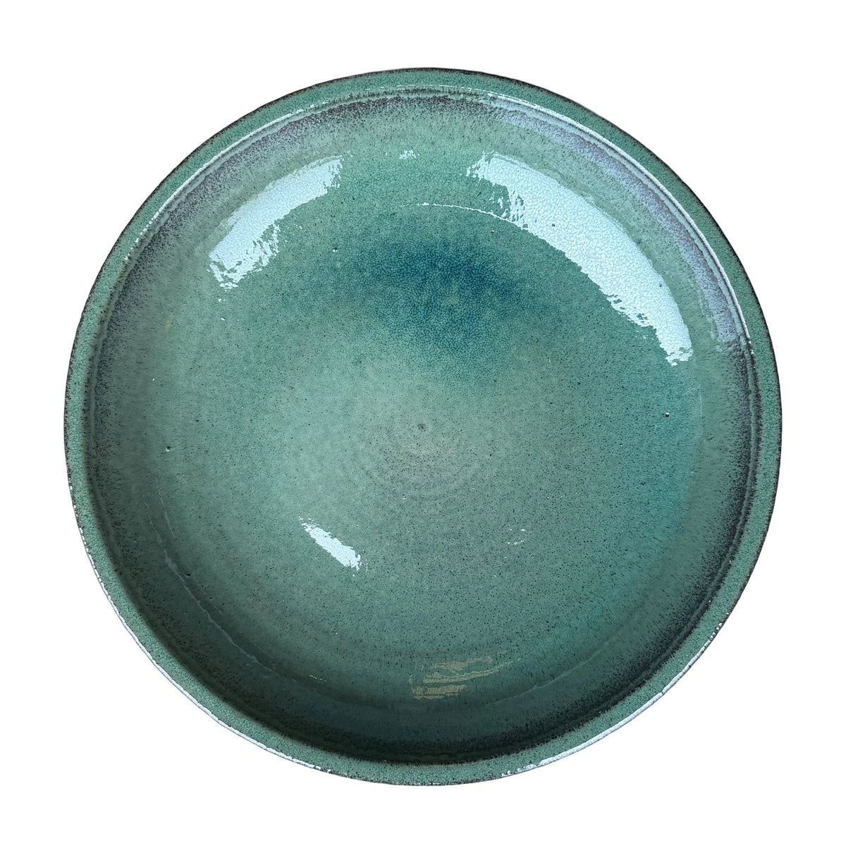 Top-down view of a teal ceramic bird bath bowl, showing a wide glossy basin with deeper blue pooling and a dark-flecked rim.