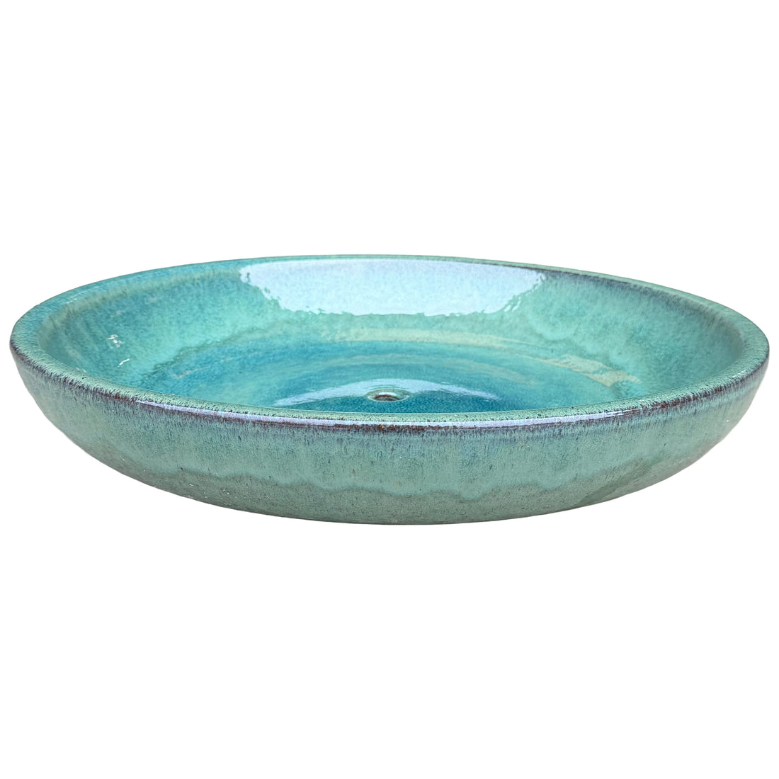 Angled view of a wide, shallow teal ceramic succulent bowl with a glossy turquoise interior, a central drainage hole and a speckled rim with flecks of brown clay