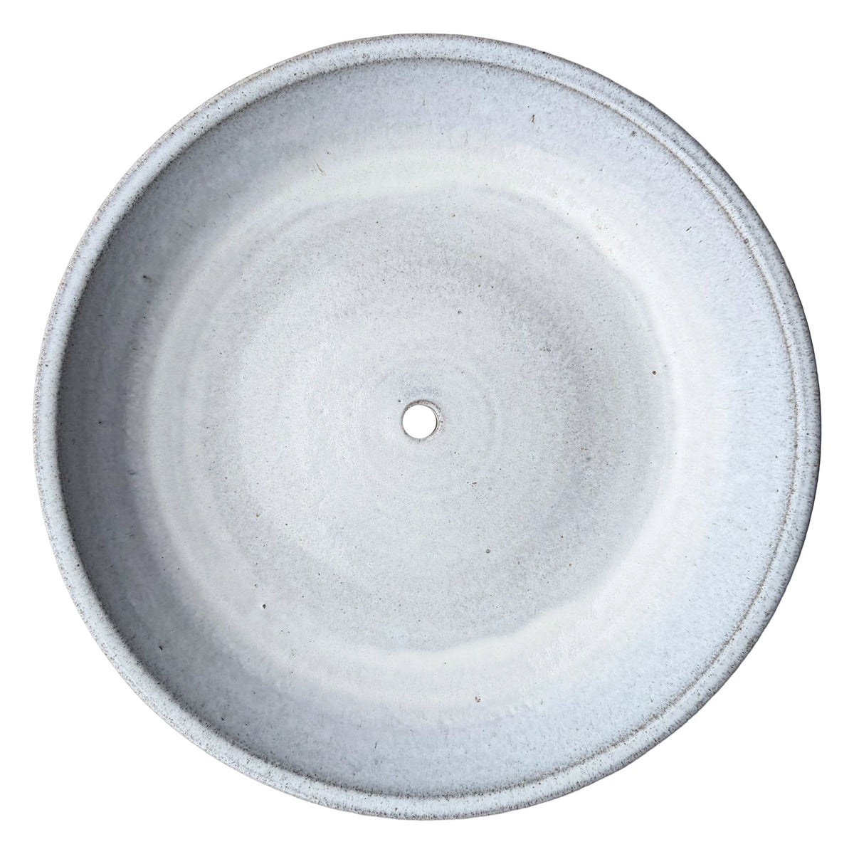 Top-down view inside a white ceramic succulent bowl, showing a wide flat planting area, a raised rim lip and a single drainage hole