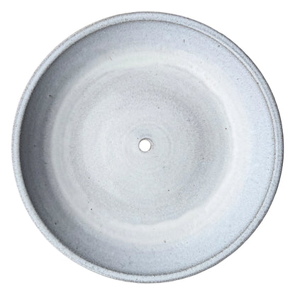 Top-down view inside a white ceramic succulent bowl, showing a wide flat planting area, a raised rim lip and a single drainage hole