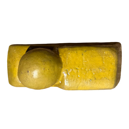 Top view of a single yellow ceramic pot foot, showing the ball and flat block where a planter rests.