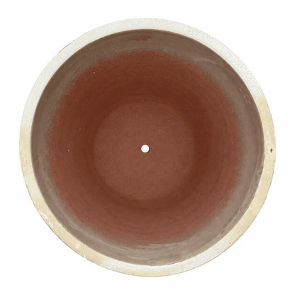 Top-down view of a a yellow spray tapered round planter, with a pale sandy rim and inner walls that fade into a terracotta-red interior with a small central drainage hole